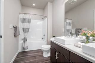 A white toilet sits in a bathroom next to a sink at Aventura at Wentzville I & II Apartments, Wentzville