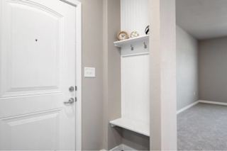 A white door is on the left and a white shelf with clocks and other items is on the right at Aventura at Wentzville I & II Apartments, Wentzville, MO, 63385