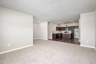 A spacious living room with a kitchen in the background at Aventura at Wentzville I & II Apartments, Wentzville, MO