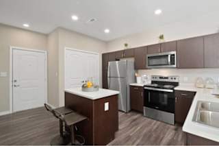 A kitchen with brown cabinets and a white island at Aventura at Wentzville I & II Apartments, Wentzville, Missouri