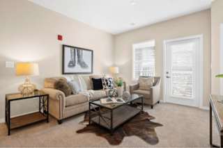 A living room with a couch, a coffee table, and a painting of boots on the wall at Aventura at Wentzville I & II Apartments, Wentzville, MO, 63385
