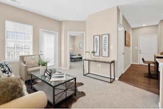A living room with a glass coffee table and a brown furry chair at Aventura at Wentzville I & II Apartments, Wentzville, MO