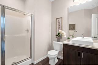 A white toilet sits in a bathroom next to a sink and a shower at Aventura at Wentzville I & II Apartments, Wentzville