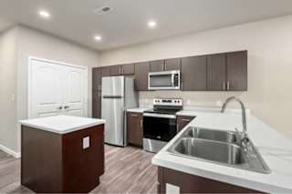 A kitchen with brown cabinets and white countertops at Aventura at Wentzville I & II Apartments, Wentzville, Missouri