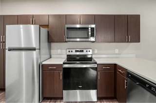 A modern kitchen with a stainless steel refrigerator, microwave, and oven at Aventura at Wentzville I & II Apartments, Missouri, 63385