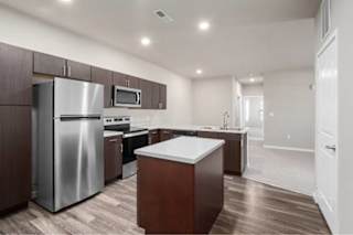 A modern kitchen with dark wood cabinets and stainless steel appliances at Aventura at Wentzville I & II Apartments, Missouri