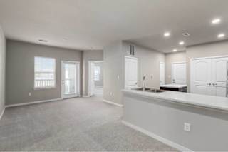 A spacious room with a carpeted floor, a window with a view, and a counter with a sink at Aventura at Wentzville I & II Apartments, Wentzville, MO