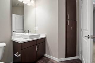 A bathroom with a white sink and brown cabinetry at Aventura at Wentzville I & II Apartments, Wentzville, Missouri