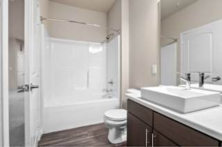 A white bathroom with a toilet, sink, and bathtub at Aventura at Wentzville I & II Apartments, Wentzville
