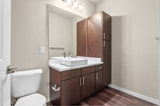 A bathroom with a white toilet and a white sink with brown cabinets at Aventura at Wentzville I & II Apartments, Wentzville, MO, 63385