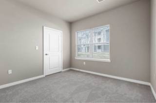 A room with a white door and a window showing a building outside at Aventura at Wentzville I & II Apartments, Missouri
