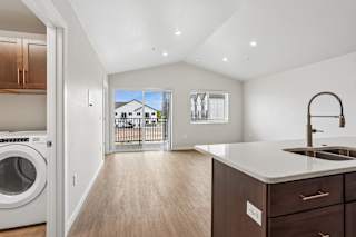 A modern kitchen with a washing machine and a view of a house through the window.
