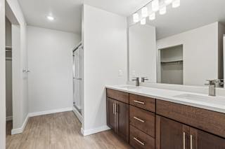 A bathroom with a white sink and brown cabinets.