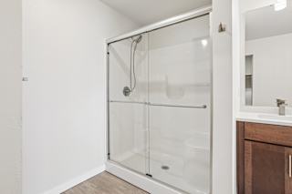 A white bathroom with a walk-in shower and a white sink.