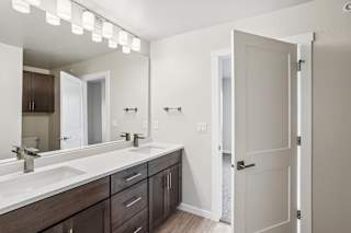 A bathroom with a white sink and brown drawers.