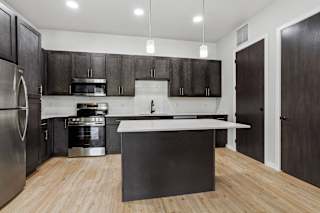 A modern kitchen with dark wood cabinets and a white island.