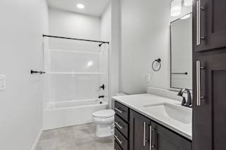 A white bathroom with a toilet, sink, and shower.