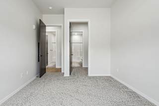 A white room with a carpeted floor and a door on the left.