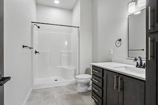 A modern bathroom with a walk-in shower, toilet, and sink.