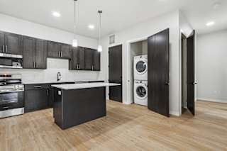 A modern kitchen with black cabinets and a wooden floor.