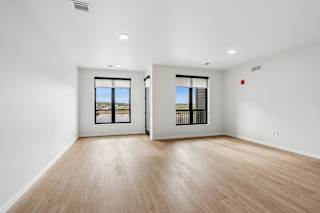A large empty room with wooden floors and windows.