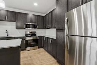 A modern kitchen with dark wood cabinets and stainless steel appliances.