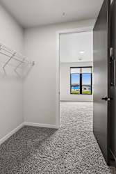 A room with a grey carpet and a window overlooking the ocean.