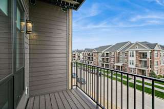A balcony with a black railing and a view of apartment buildings.