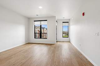 A room with a wooden floor and a window showing a view of a house.