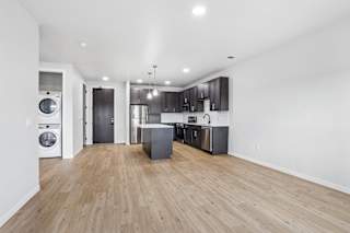 A spacious kitchen with wooden floors and modern appliances.