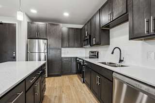 A modern kitchen with dark wood cabinets and stainless steel appliances.