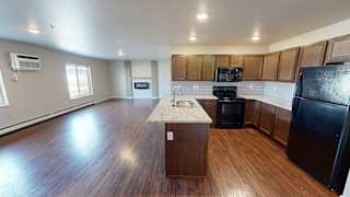 an empty kitchen with wood flooring and black appliances