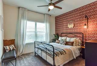 Bedroom with terracotta accent wall and ceiling fan 1 at High Point Preserve Apartments, Austin, Texas