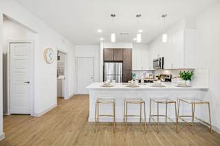 A kitchen with a bar area and four stools. at ThreeTwenty at the Vybe Apartments, Texas, 78640