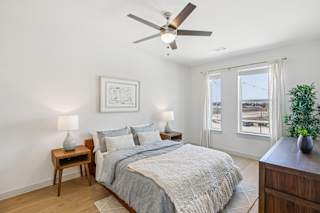 A bedroom with a bed, a ceiling fan, and a plant at ThreeTwenty at the Vybe Apartments, Kyle