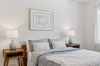 A bedroom with a bed, two lamps, and a painting on the wall at ThreeTwenty at the Vybe Apartments, Kyle, TX