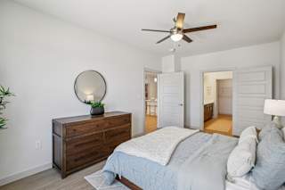 A bedroom with a bed, dresser, and mirror. at ThreeTwenty at the Vybe Apartments, Kyle, TX