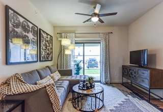 Living room with gray sectional sofa and patterned rug at High Point Preserve Apartments, Texas, 78724