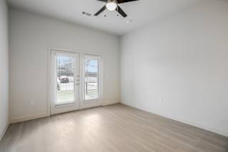 Empty room with french doors and ceiling fan at Cantarra Apartments, Manor, Texas