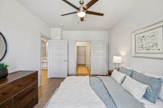A bedroom with a bed, dresser, and mirror at ThreeTwenty at the Vybe Apartments, Texas