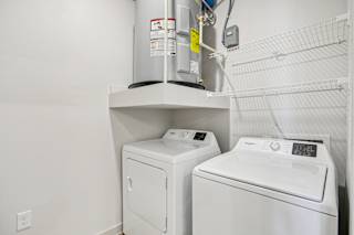 A wall-mounted washer and dryer are installed in a small room. at ThreeTwenty at the Vybe Apartments, Texas