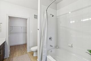 A white bathroom with a white tub and toilet. at ThreeTwenty at the Vybe Apartments, Kyle, TX