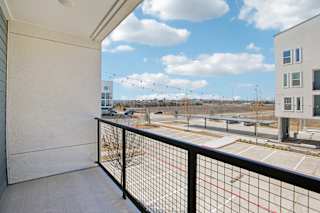 A balcony with a black railing overlooks a parking lot and buildings at ThreeTwenty at the Vybe Apartments, Texas, 78640