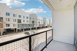 A view of a balcony with a black railing and a red line on the ground at ThreeTwenty at the Vybe Apartments, Kyle, TX