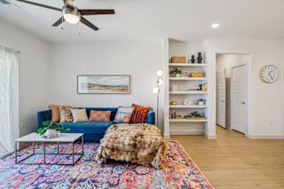 A living room with a blue couch and a colorful rug at ThreeTwenty at the Vybe Apartments, Kyle, TX, 78640
