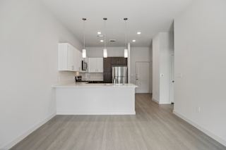Open kitchen with white island and wood flooring at Cantarra Apartments, Manor, TX 78653