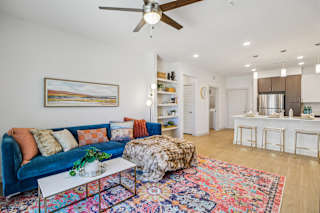 A living room with a blue couch and a colorful rug. at ThreeTwenty at the Vybe Apartments, Kyle, TX, 78640