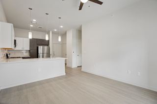 Open living area with modern kitchen and pendant lights at Cantarra Apartments, Manor, TX