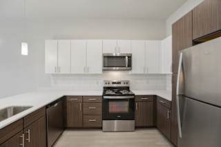 Modern kitchen with white and wood cabinetry at Cantarra Apartments, Manor