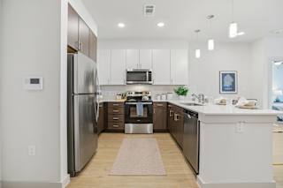 A modern kitchen with a refrigerator, microwave, and oven. at ThreeTwenty at the Vybe Apartments, Texas, 78640